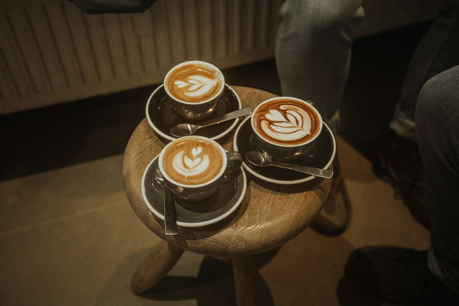 Three cups of latte art coffee on a small wooden table