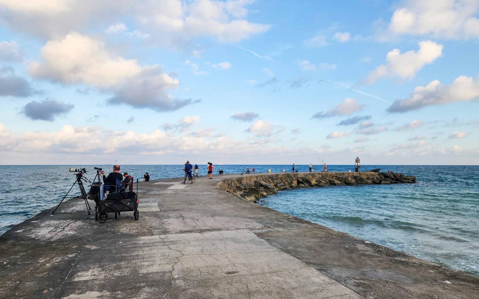 A person sitting at the end of a jetty overlooking the ocean