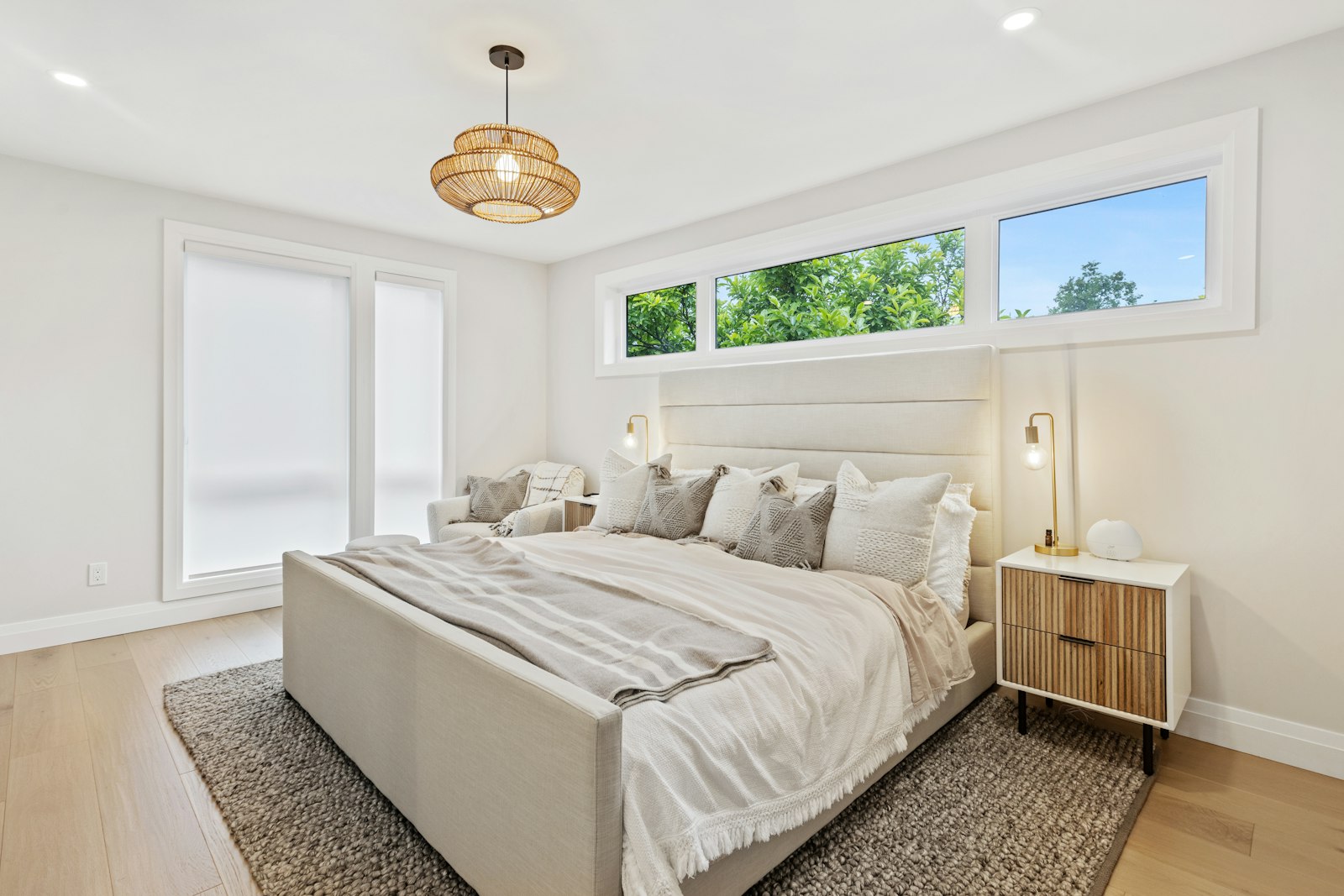 A bright, neatly made bedroom with large windows