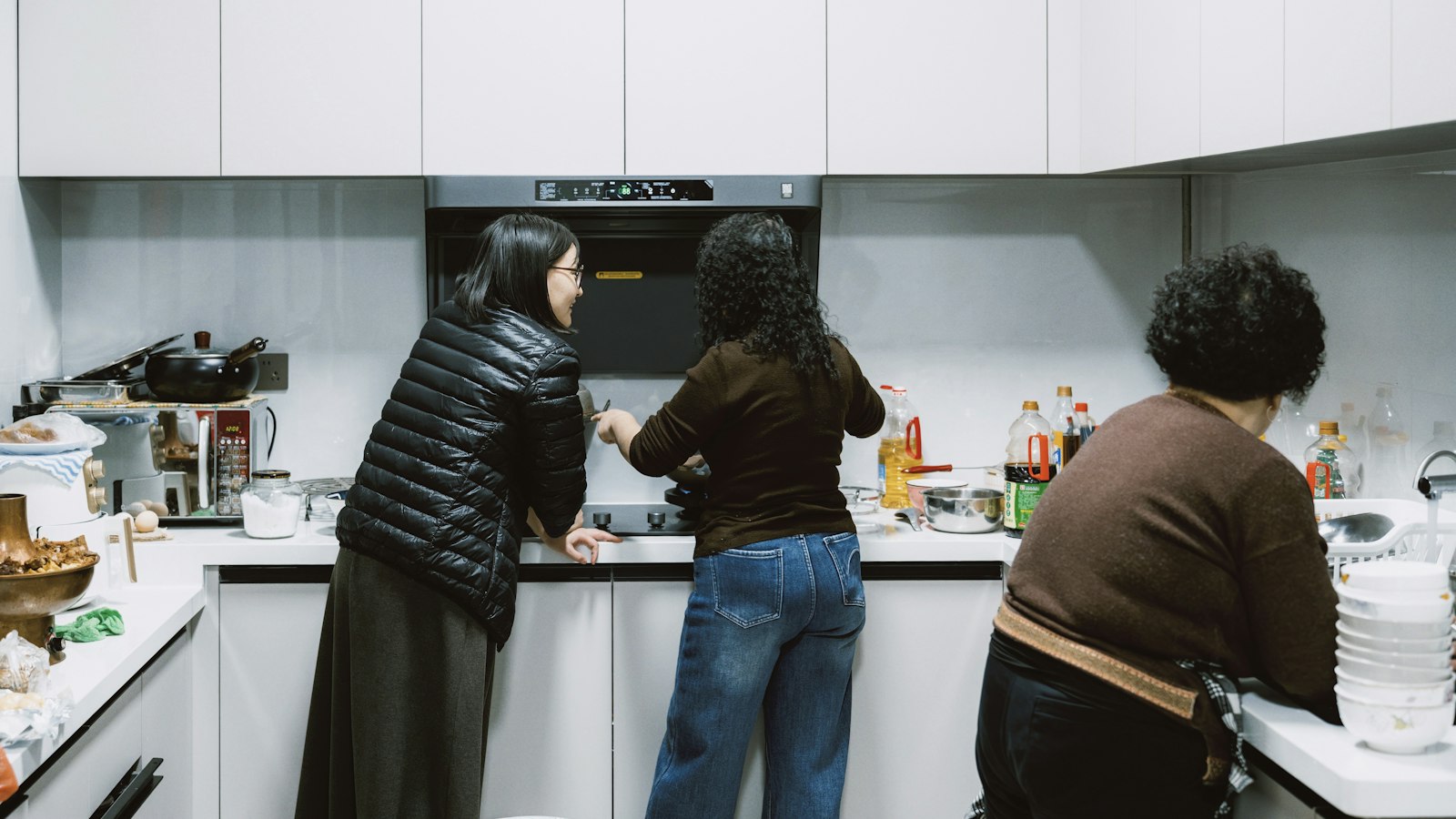 Three people preparing food together in a modern kitchen