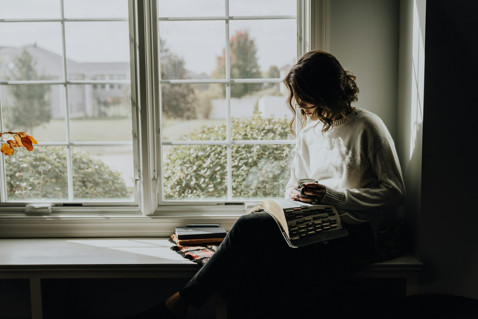 A woman reading in a chair by a bright window