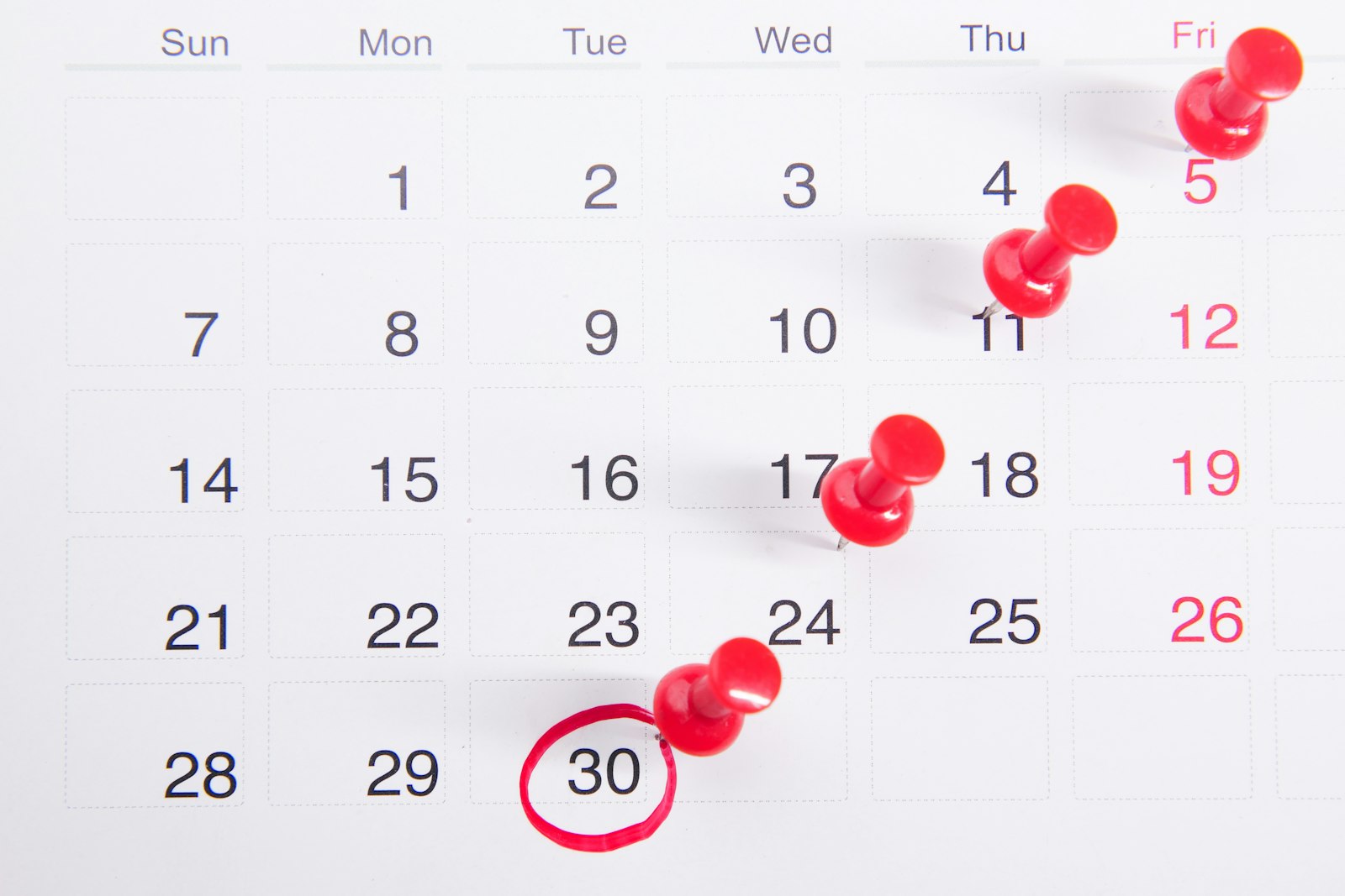 A wall calendar with dates pinned in red