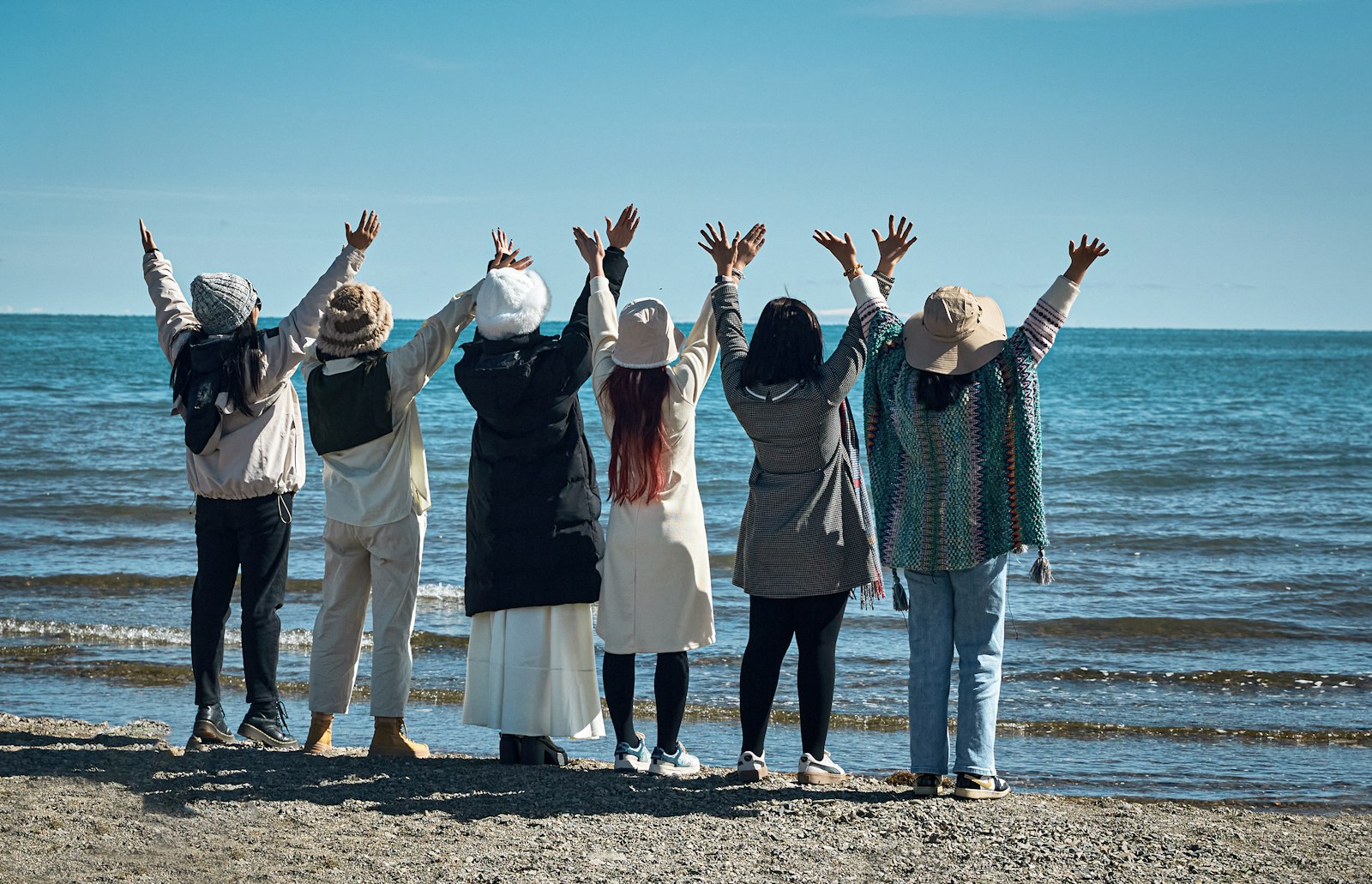 Friends with arms raised on the beach
