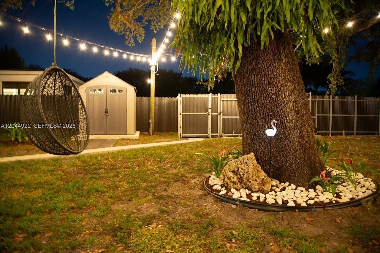 Garden seating under string lights beside a large tree